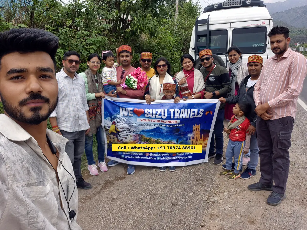 Suzu Travels team welcoming a family group in Himachal with Himachali caps and flowers