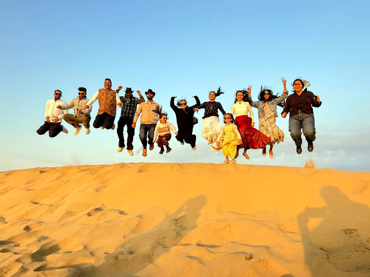 Suzu Travels family group jumping on the Jaisalmer sand dunes at sunset