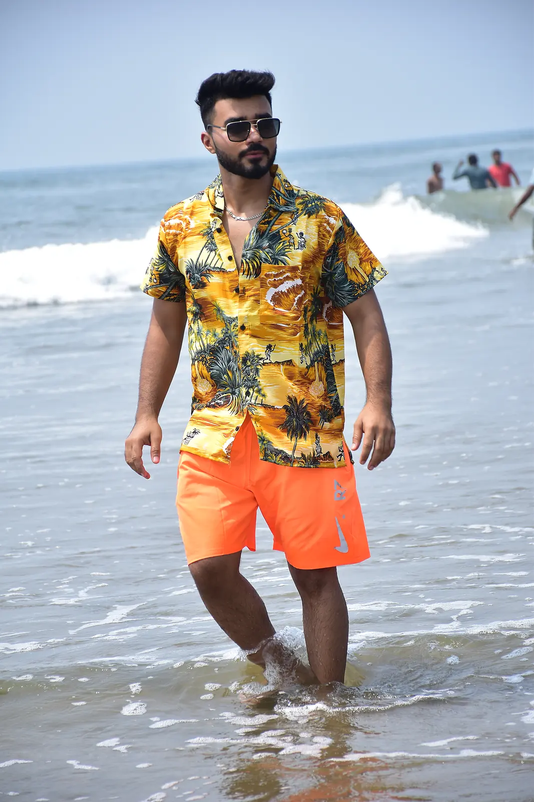 Traveller in holiday wear walking through the waves on a Goa beach