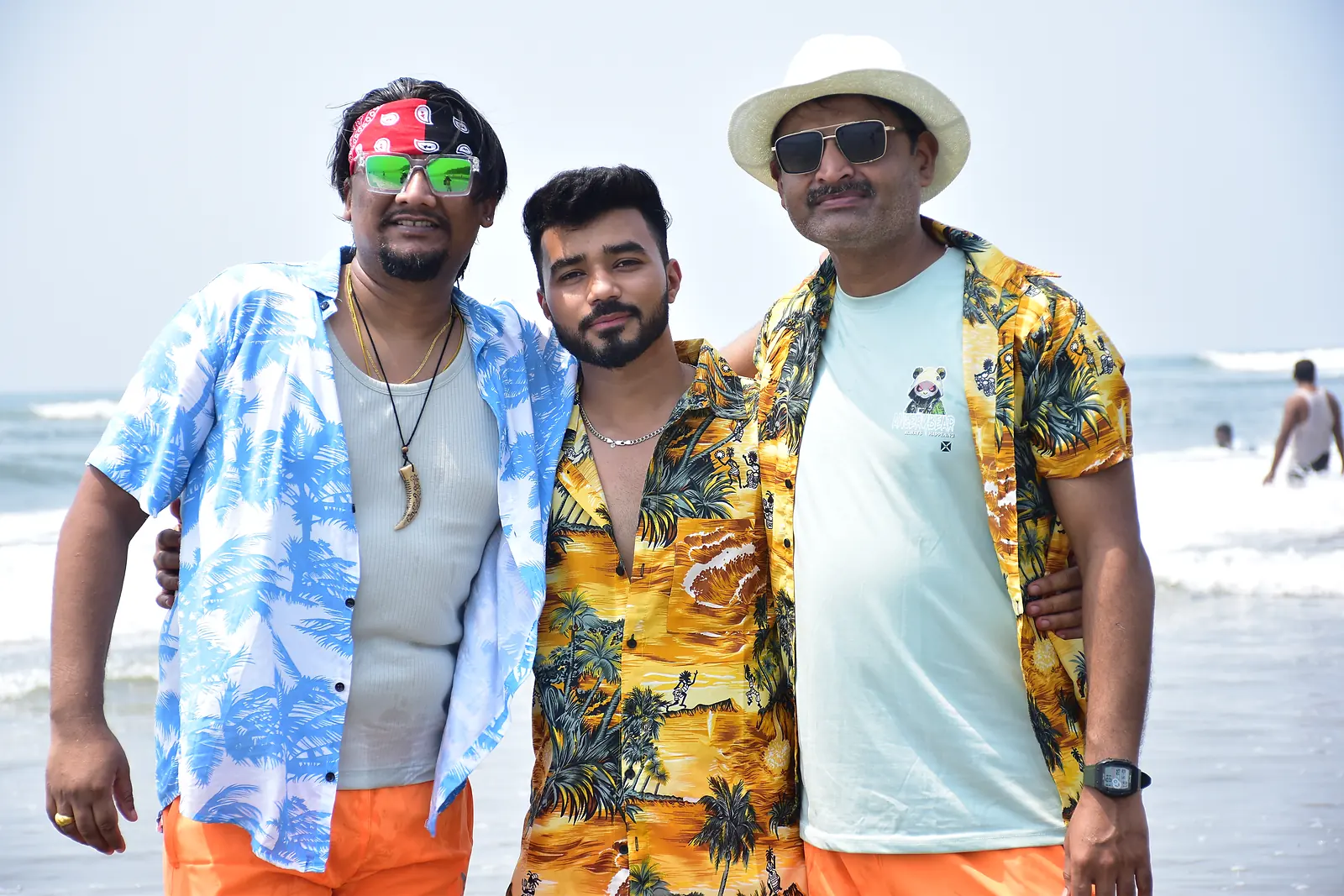 Three friends smiling on a Goa beach holiday