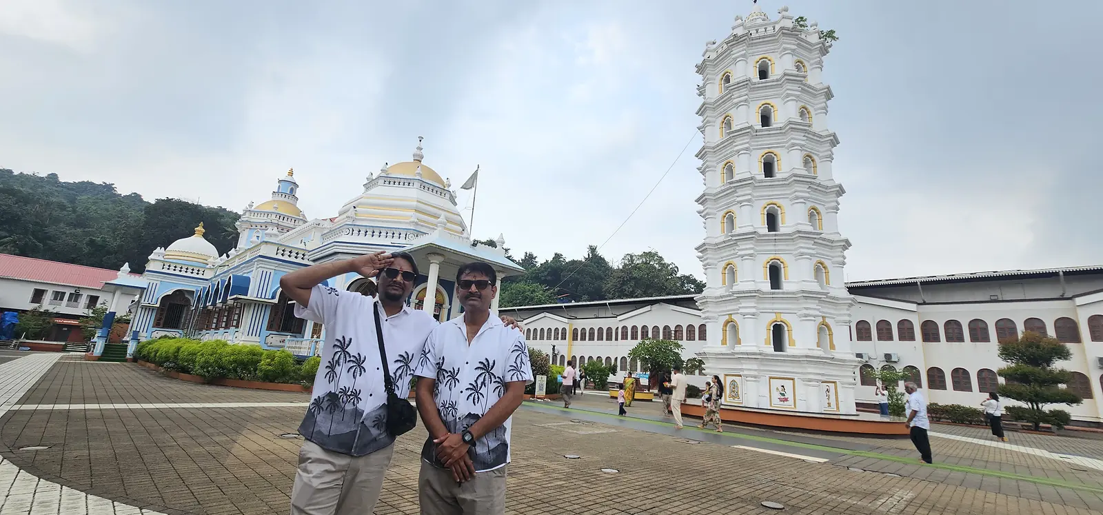 Group of travellers at a Goa temple with its lamp tower