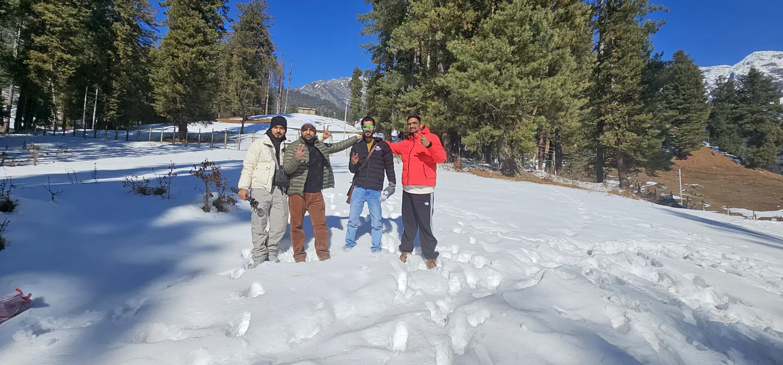 Travellers on a snowy meadow with pine forest in Pahalgam