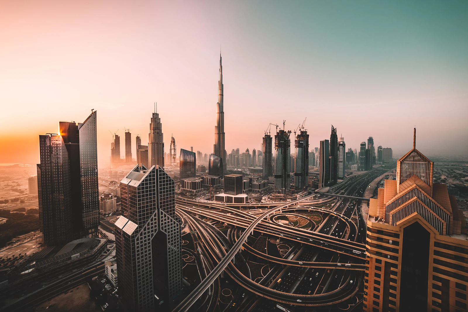 Burj Khalifa rising above the Downtown Dubai skyline and highway interchange at sunset