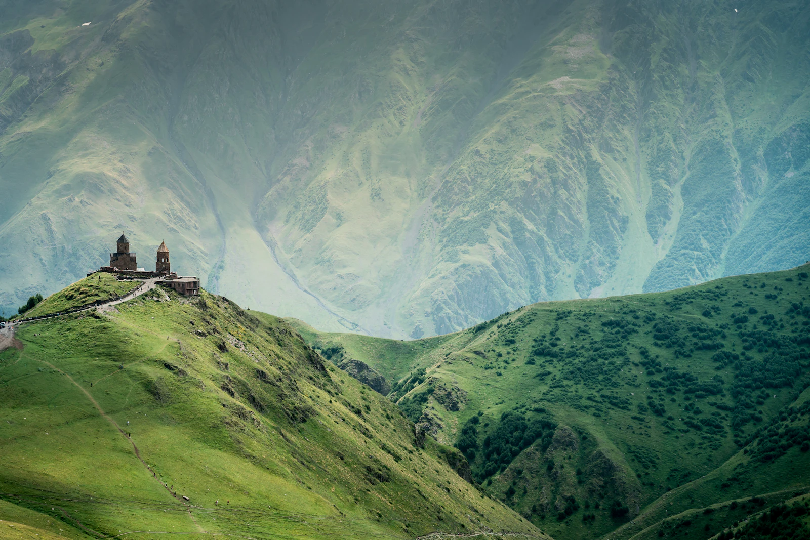 suzu abroad georgia gergeti church green ridge Gergeti Trinity Church on a grassy ridge among green Caucasus mountains near Kazbegi, Georgia