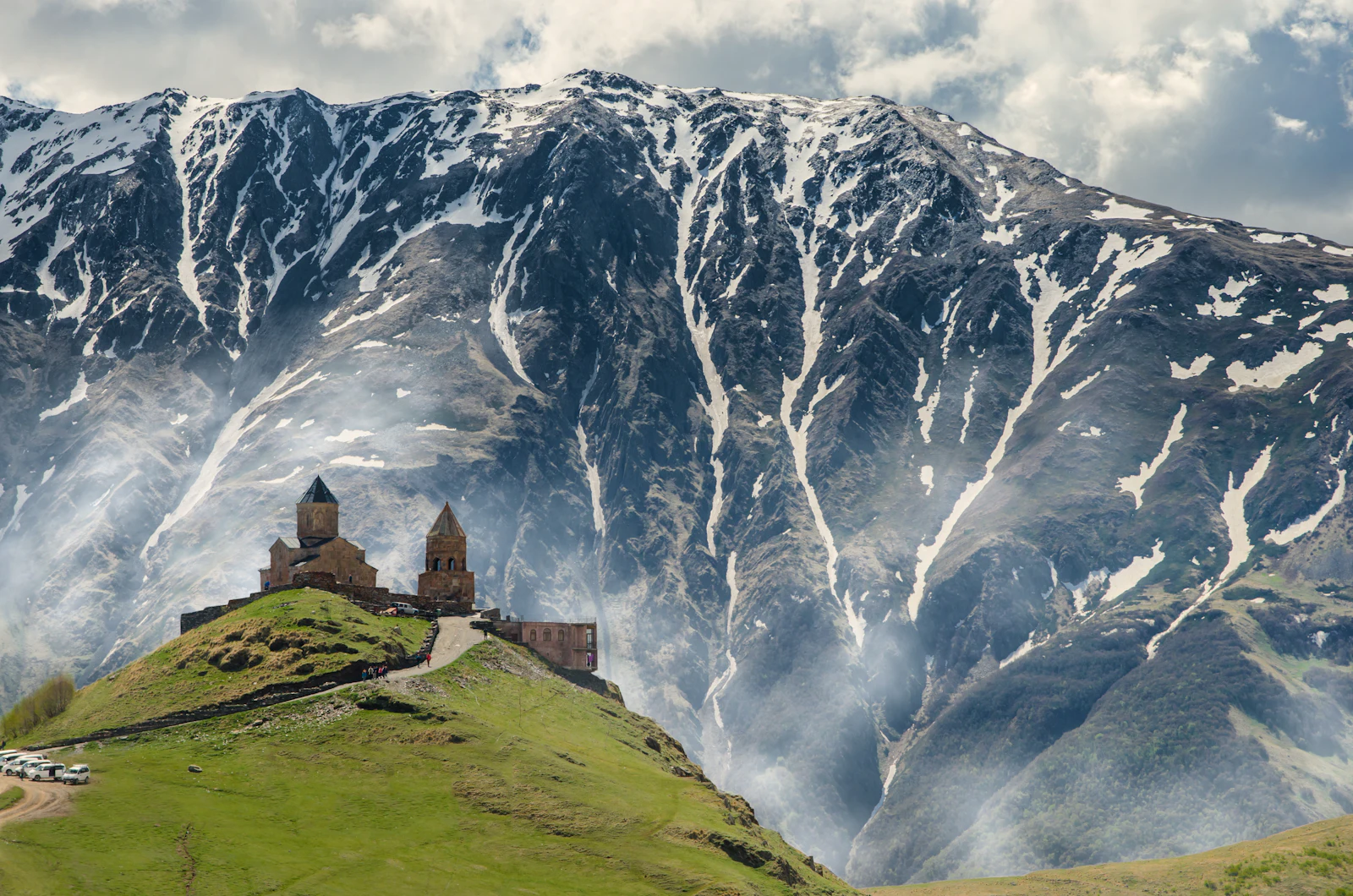 suzu abroad georgia gergeti trinity church kazbegi Gergeti Trinity Church on a green hill below snow-streaked Caucasus peaks, Kazbegi, Georgia